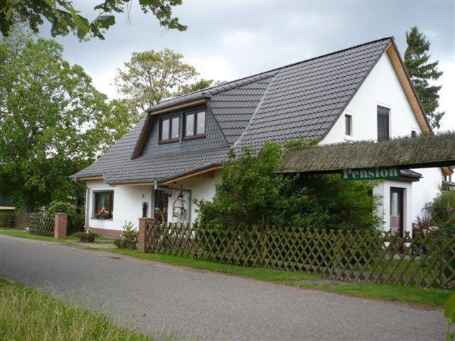a white house with a black roof on a street at Pension-Drews in Grubenhagen