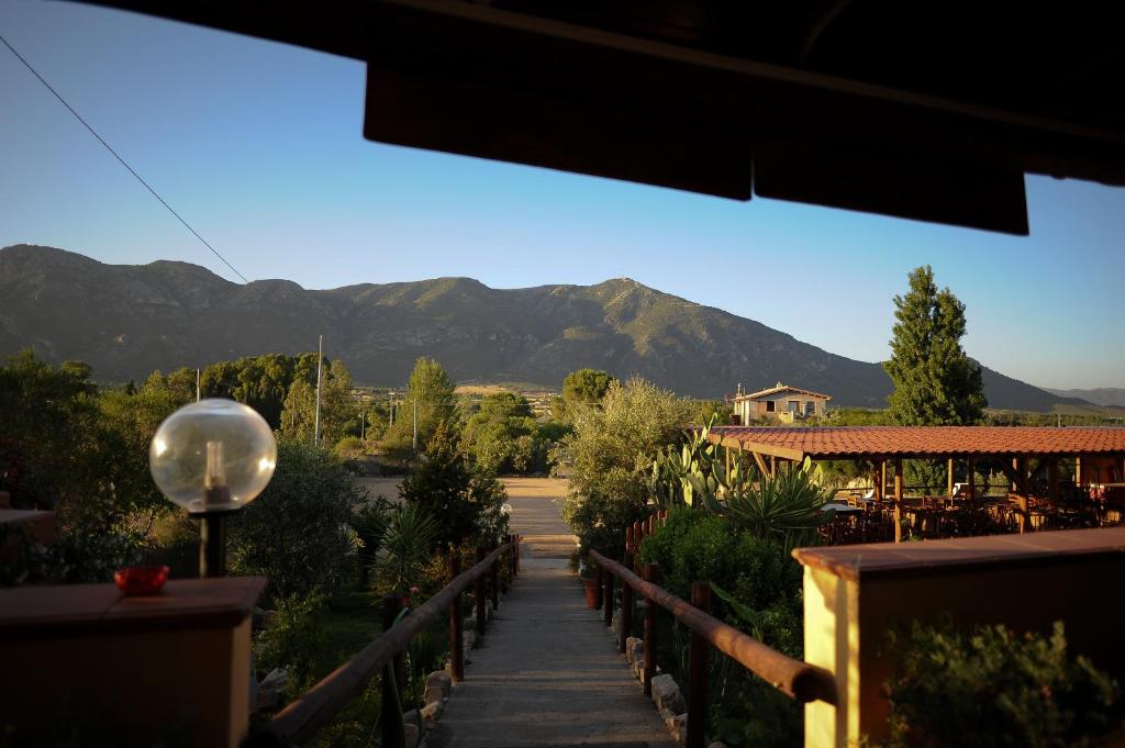 un camino que conduce a una casa con montañas en el fondo en S'arriali Ranch, en Iglesias