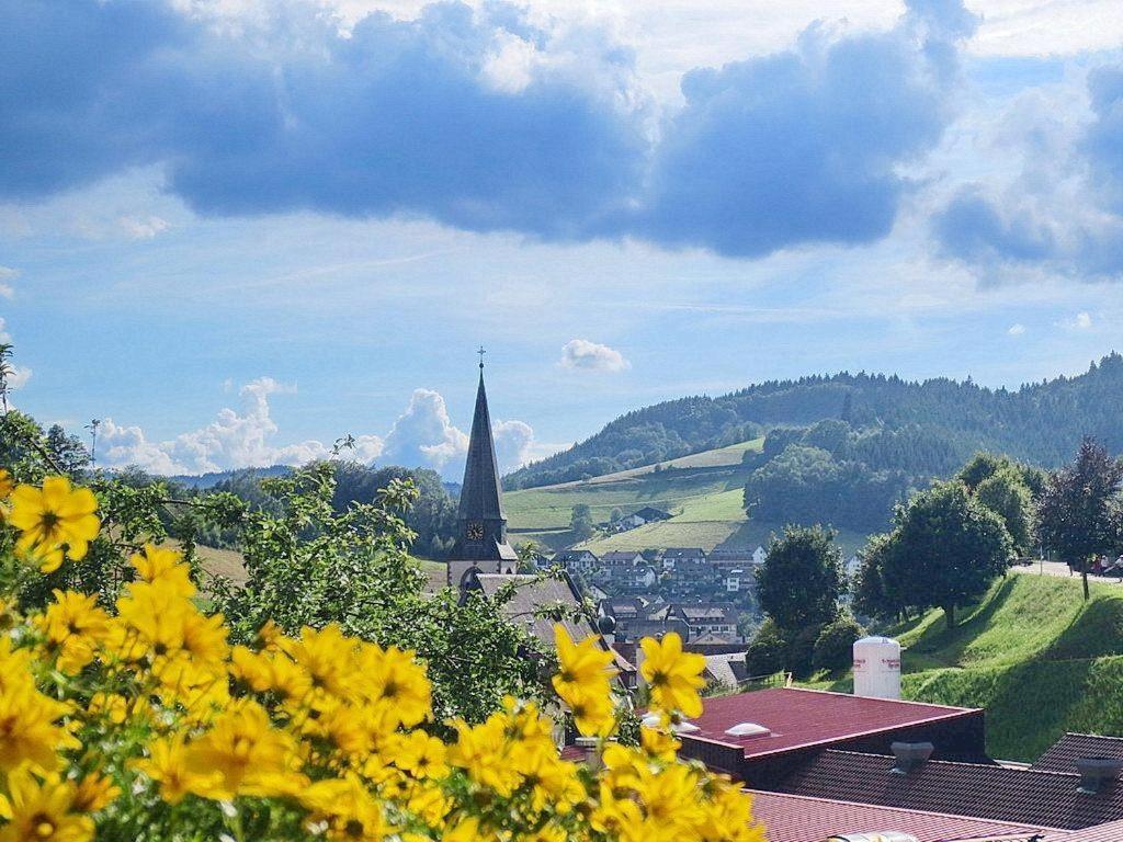 une vue sur une ville avec des fleurs jaunes au premier plan dans l'établissement Ferienwohnung am Kapellenberg - am Rande des Nationalparks Schwarzwald, à Bad Peterstal-Griesbach