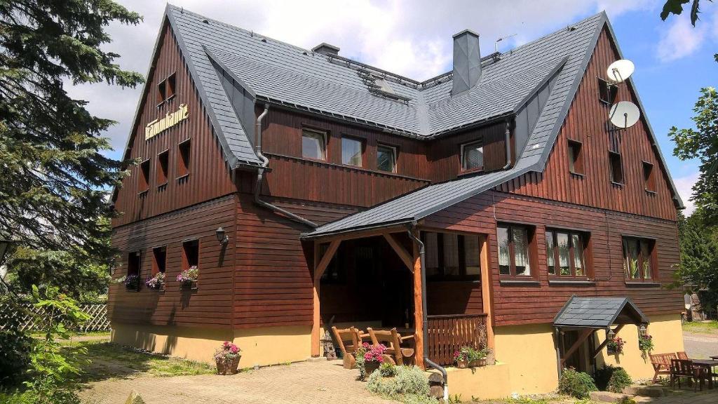 a large wooden house with a gambrel roof at Ferienwohnung-3 in Hermsdorf