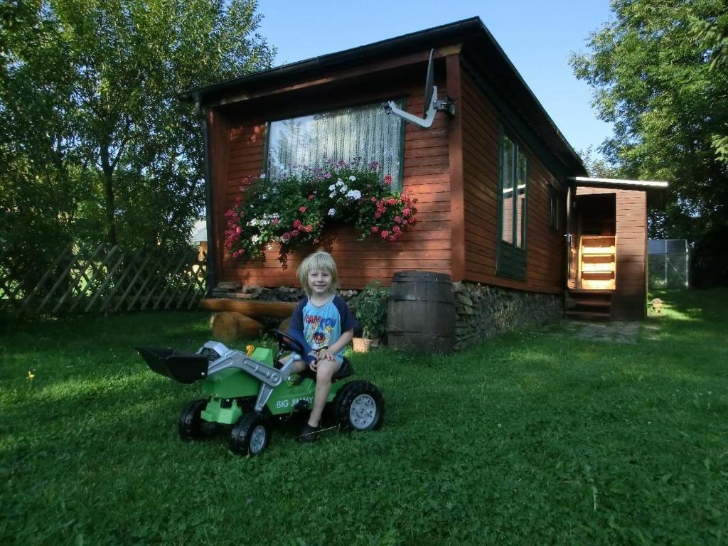 Ein kleiner Junge, der auf einem Dreirad vor einem Haus sitzt. in der Unterkunft Bungalow in Hermsdorf
