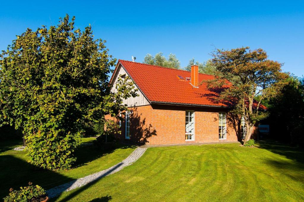 a brick house with a red roof and a yard at Ferienhaus Jan in Nordstrand