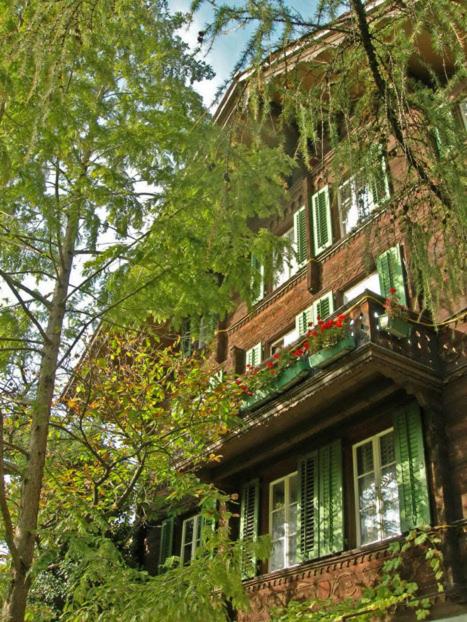 a building with green shutters and flowers on a balcony at Apartments Dr. Med. Vet. Tempelman in Interlaken