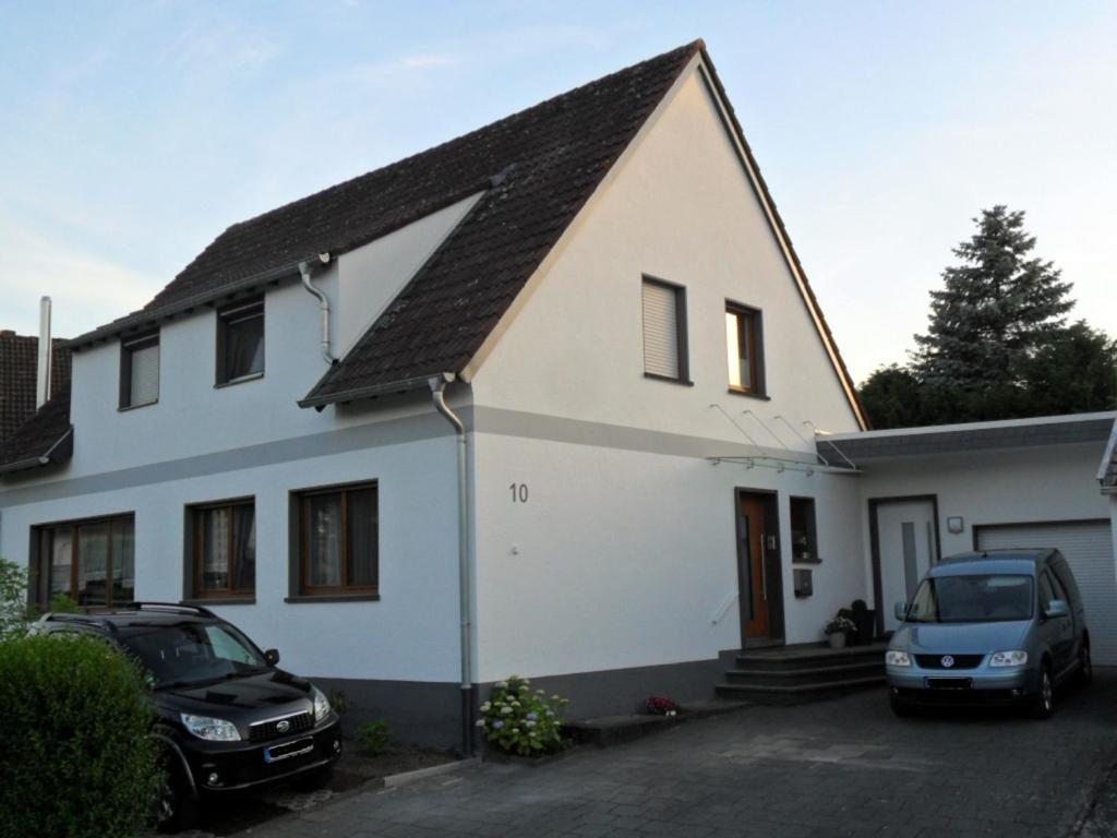 a white house with two cars parked in front of it at Ferienwohnung im Rosental in Andernach