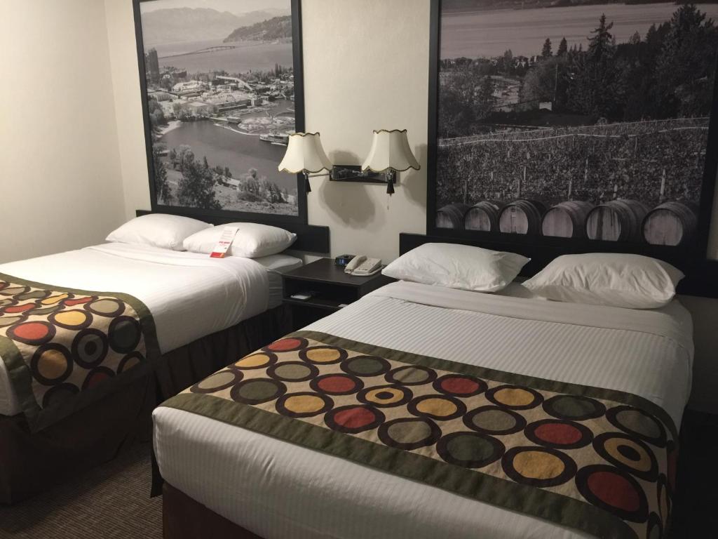 a hotel room with two beds and a painting on the wall at Super 8 by Wyndham Kelowna BC in Kelowna