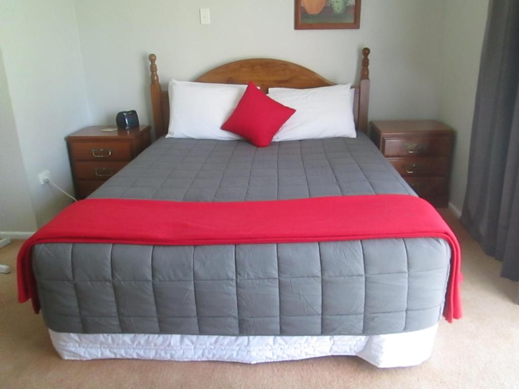 a bedroom with a large bed with a red blanket at Awatea Park Motel in Palmerston North