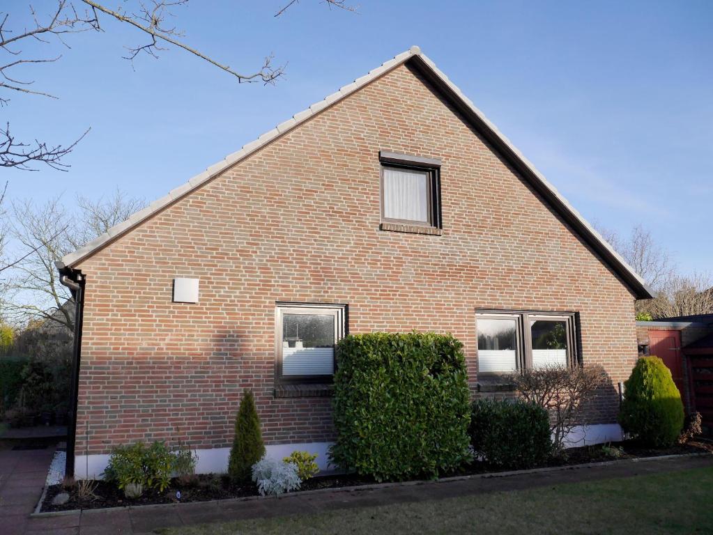 a brick house with two windows and two bushes at Ferienwohnung-Bullerby in Barkelsby