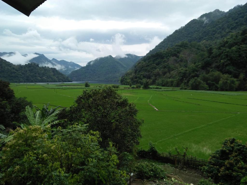 a large green field with mountains in the background at Ba Be lake-Huyền Hào Homestay in Ba Be18