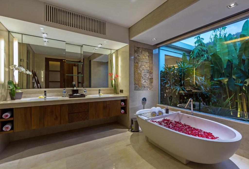 a bathroom with a large tub and a large mirror at Villa Meliya in Canggu