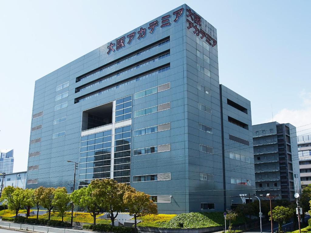 wysoki szklany budynek z napisem w obiekcie Osaka Academia w Osace