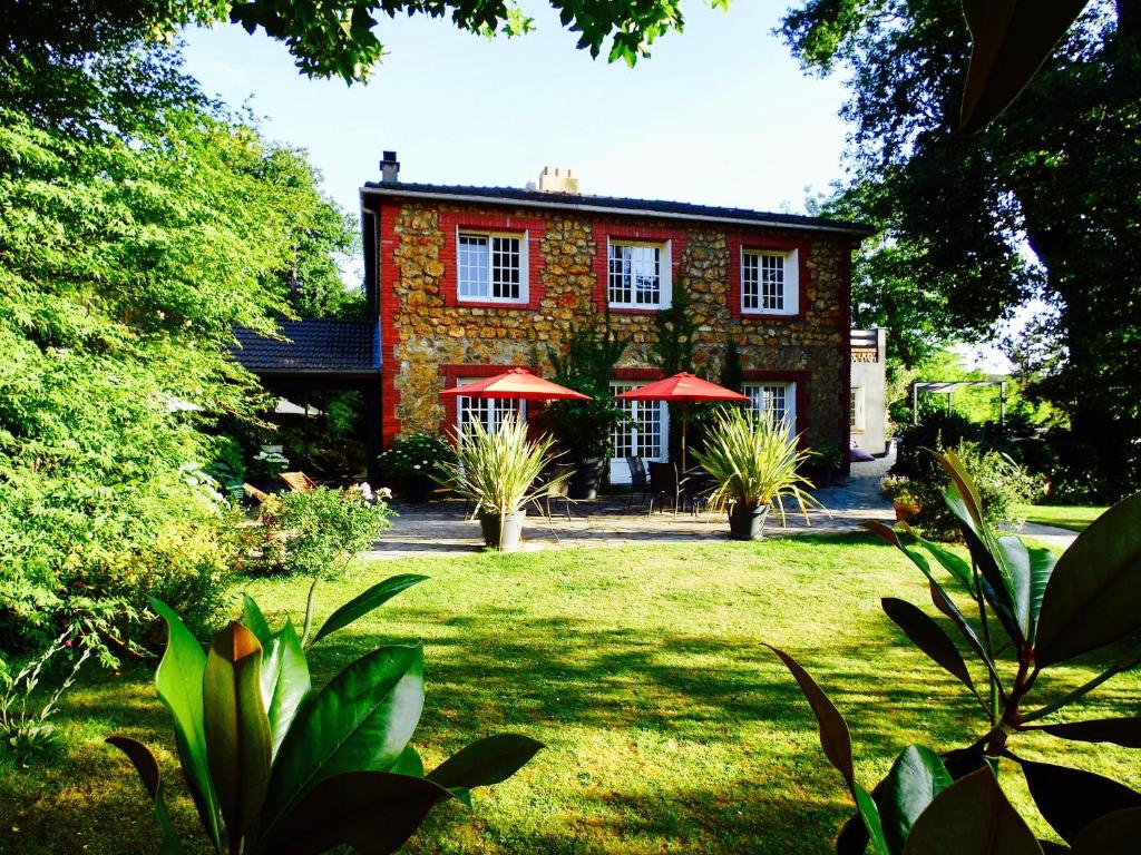 a red brick house with red umbrellas in a yard at Bed & Breakfast La Clepsydre in Fontenay-aux-Roses