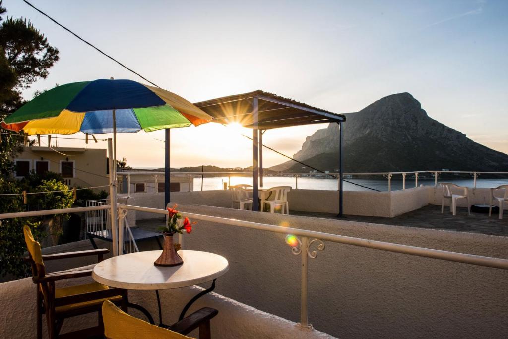 a balcony with a table and an umbrella at Hotel Aegean Home Studios & Apartments in Masouri