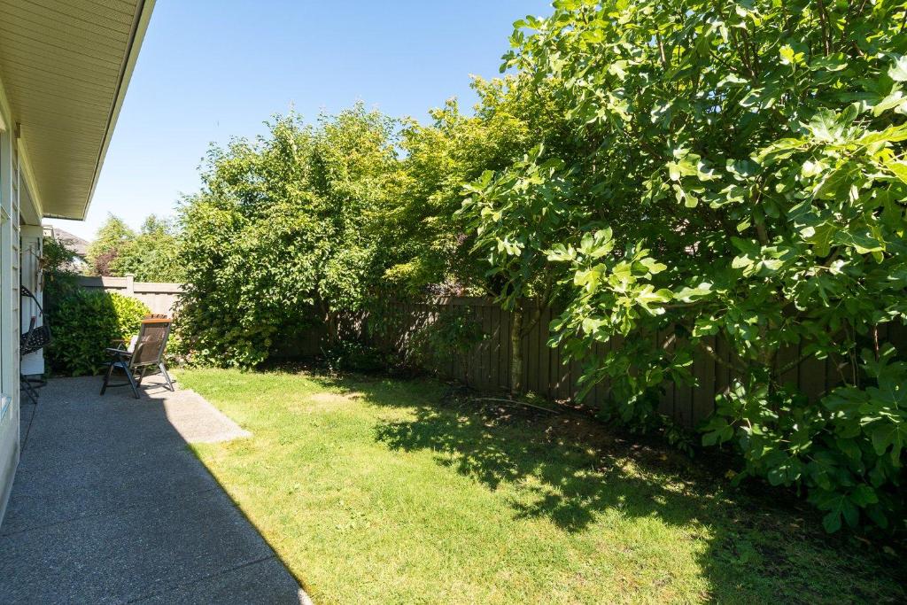 a backyard with a fence and a chair in the grass at Go House in Richmond