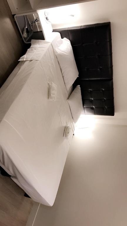 un lit avec des draps blancs et des oreillers dans une chambre dans l'établissement Suite Cocoon Paris, à Paris