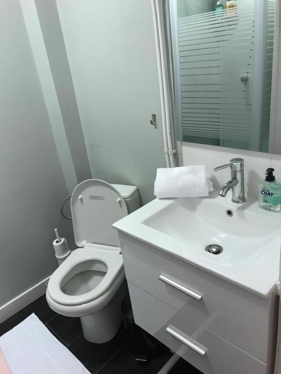 La salle de bains blanche est pourvue de toilettes et d'un lavabo. dans l'établissement Suite Cocoon Paris, à Paris