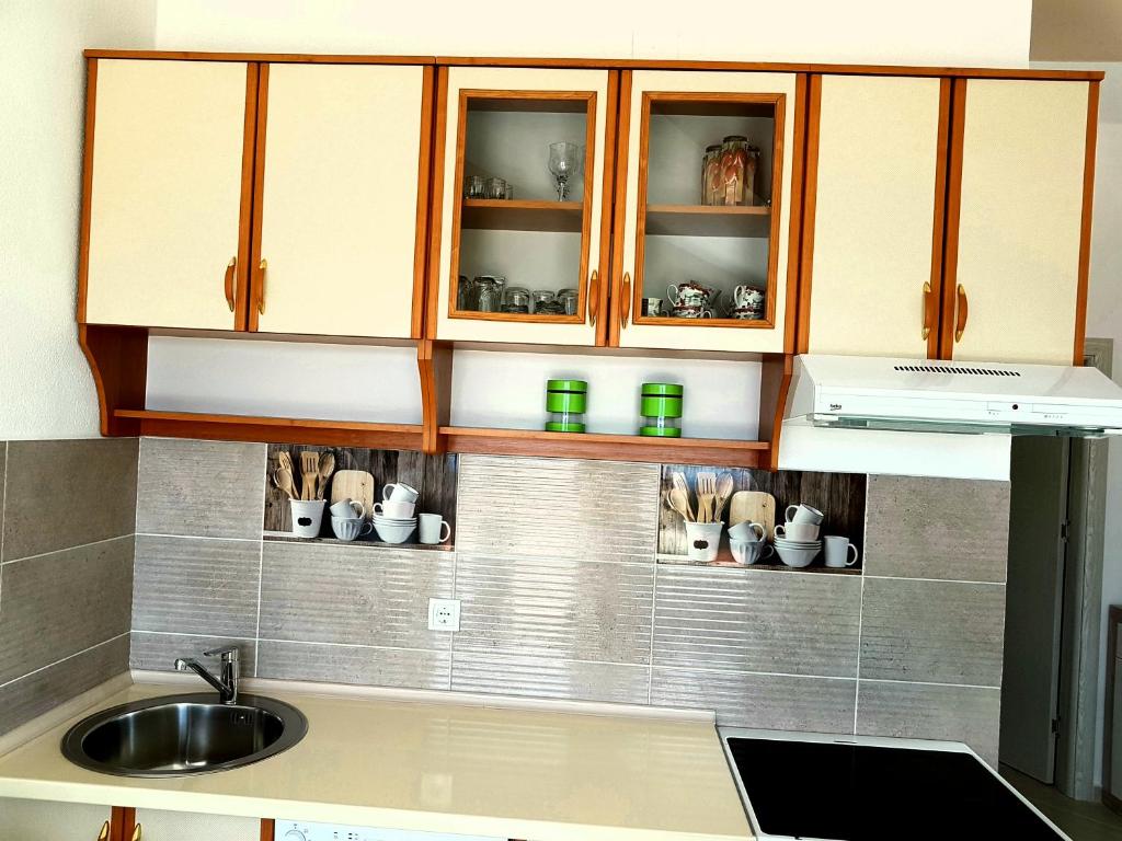 a kitchen with a sink and cabinets with cups at Apartman Milovic in Tivat