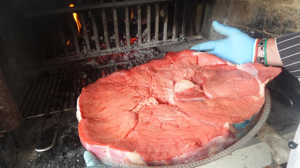 una persona sosteniendo un gran trozo de carne en un horno en Albergo Ristorante K2, en Roana