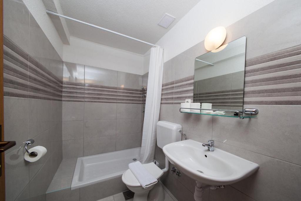 ein Badezimmer mit einem Waschbecken, einem WC und einem Spiegel in der Unterkunft Apartments Kovačić in Makarska