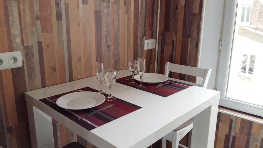 a white table with two plates and wine glasses at Studio "La Plage" - 50m Front de Mer in Berck-sur-Mer