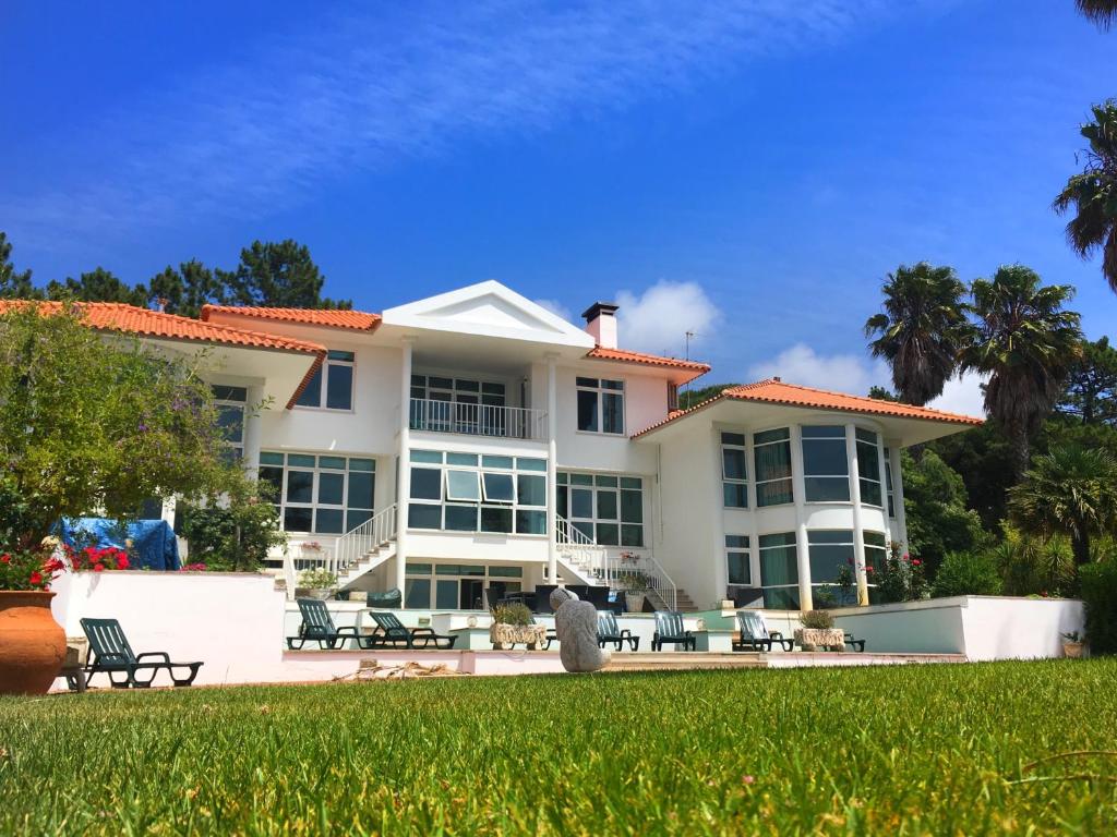 a large white building with chairs and a yard at Casa Branca Guest House in Foz do Arelho