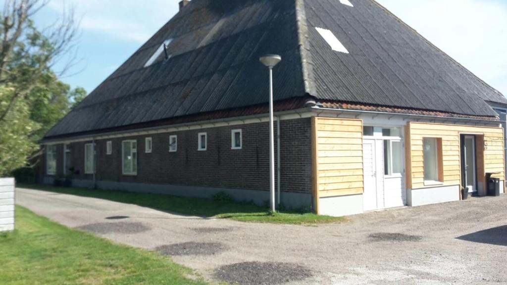 ein großes Backsteingebäude mit schwarzem Dach in der Unterkunft Apartment Vredehof in Sint Maartensbrug