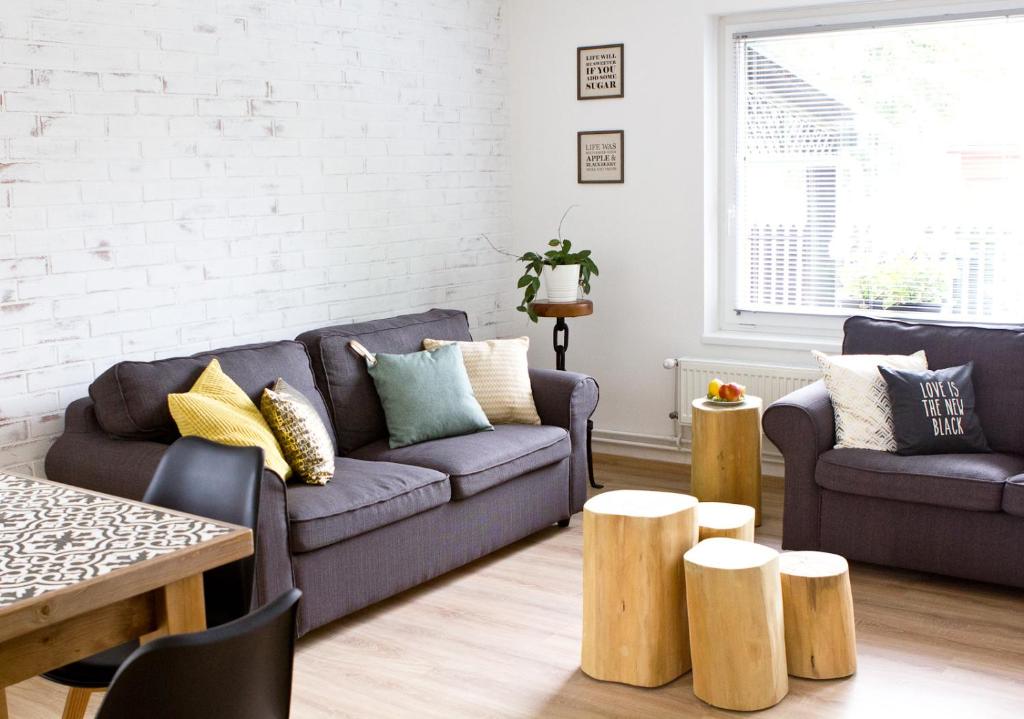 a living room with two couches and wooden stools at Zöldbarát Vendégház in Nyíregyháza