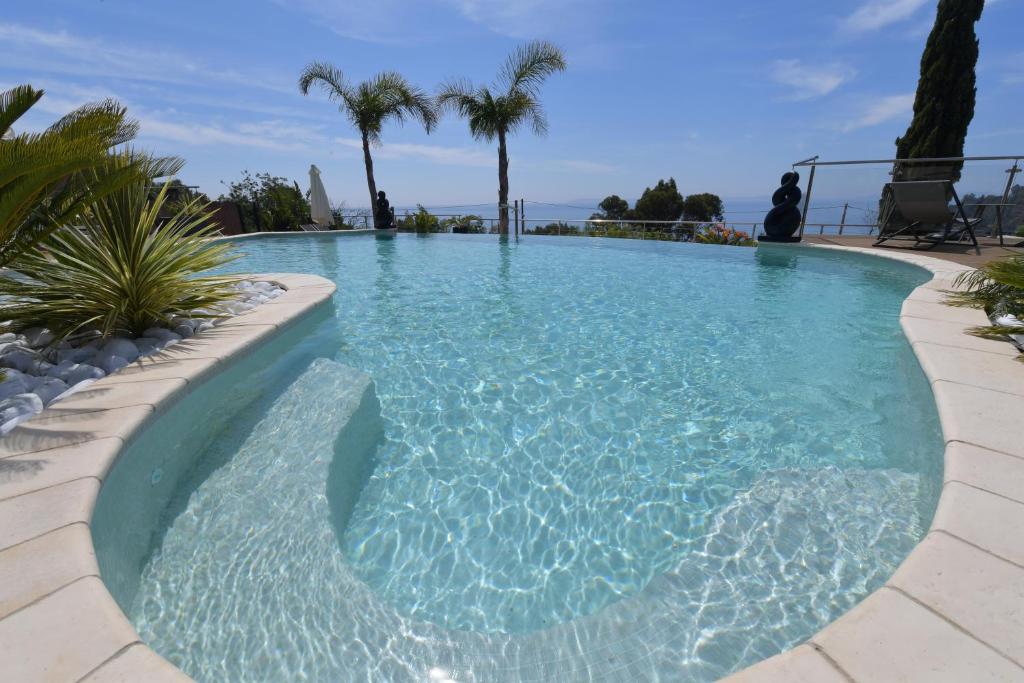 una piscina con agua azul y palmeras en Les Lauriers Roses, en Rayol-Canadel-sur-Mer