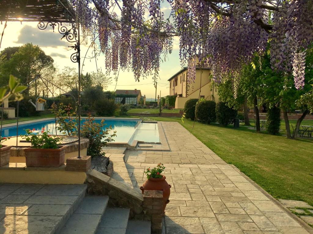 a backyard with a swimming pool and a tree with purple flowers at Agrisalotto in Cortona