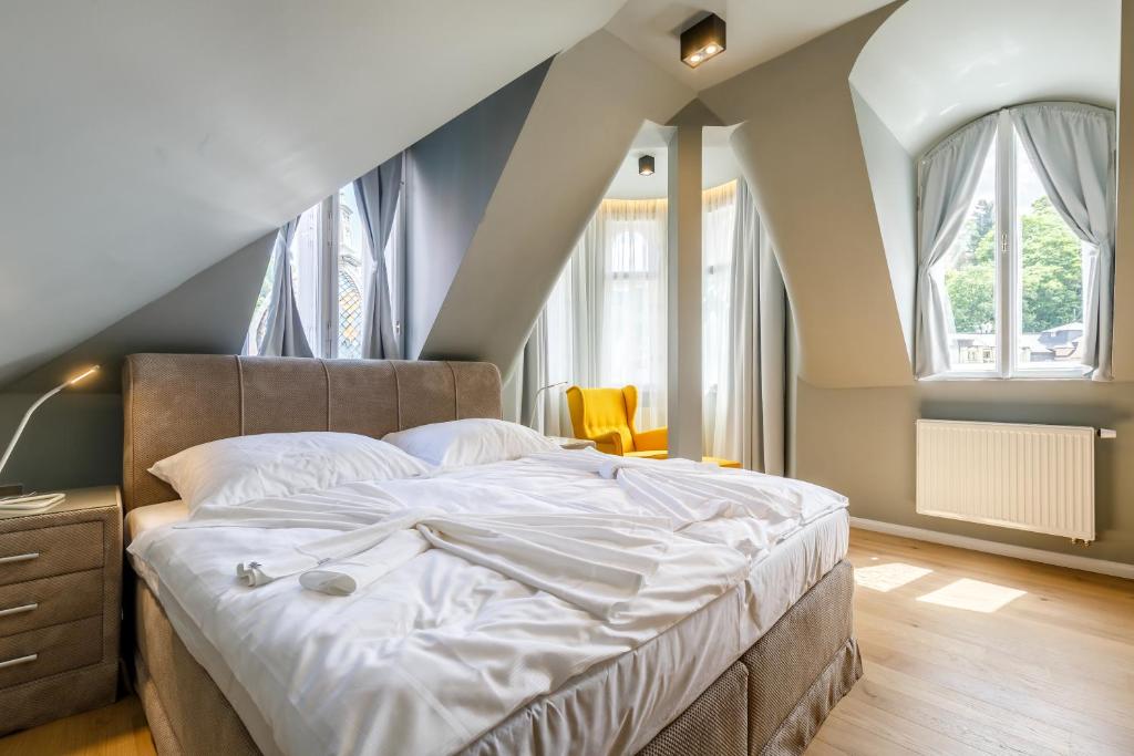 1 dormitorio con 1 cama grande con sábanas blancas en Apartments Bohemia Rhapsody, en Karlovy Vary
