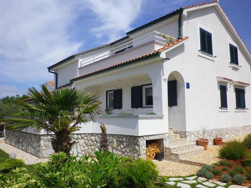 a white house with a palm tree in front of it at Apartments Marinovic in Brzac