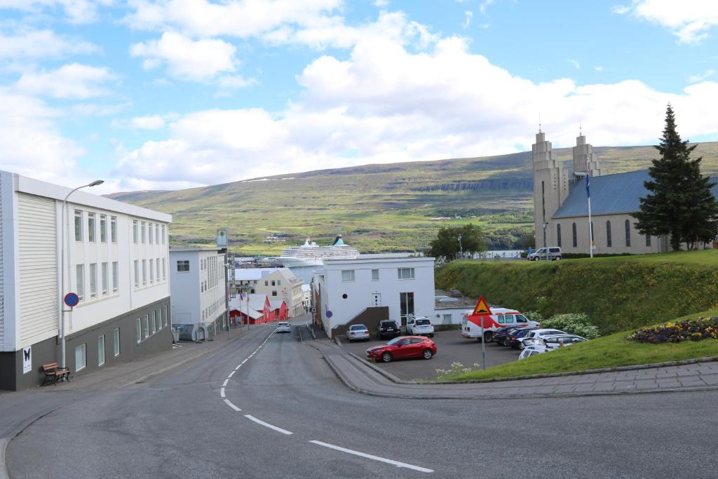 a street in a small town with a church and cars at K16Apartments in Akureyri