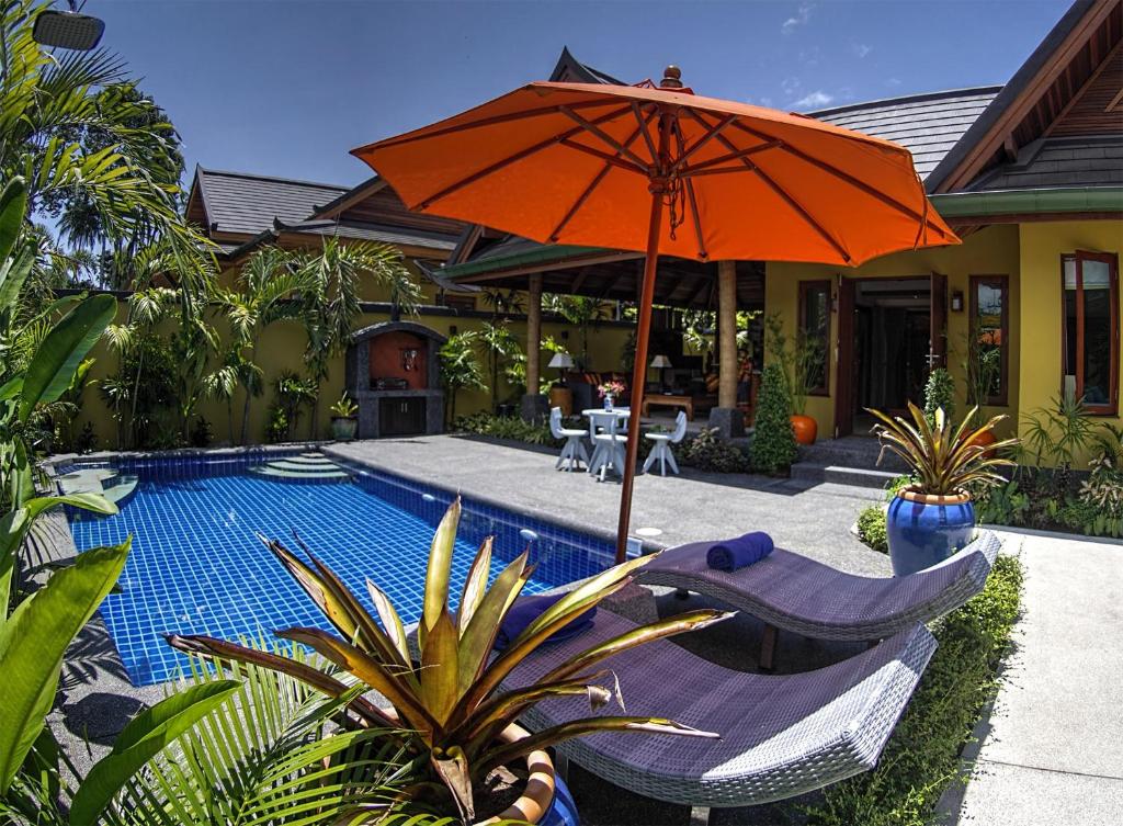 una sombrilla naranja y sillas junto a una piscina en Villa Amber, en Laem Set Beach