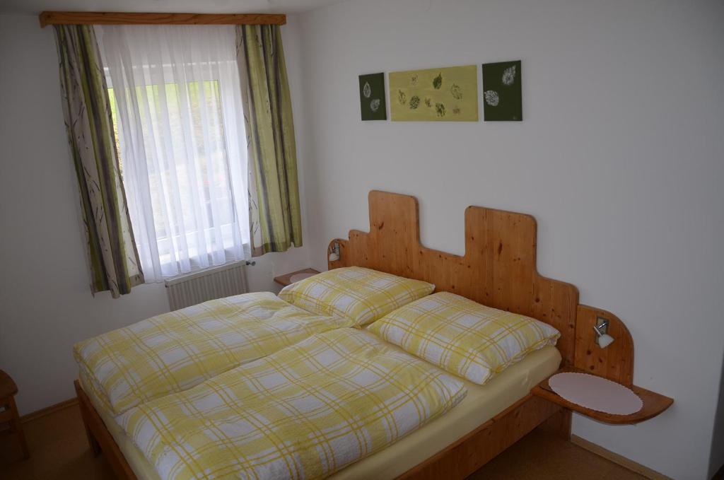 エンゲルハートシュツェルにあるHaus Donaublickのベッドルーム1室(木製ヘッドボードと窓付)