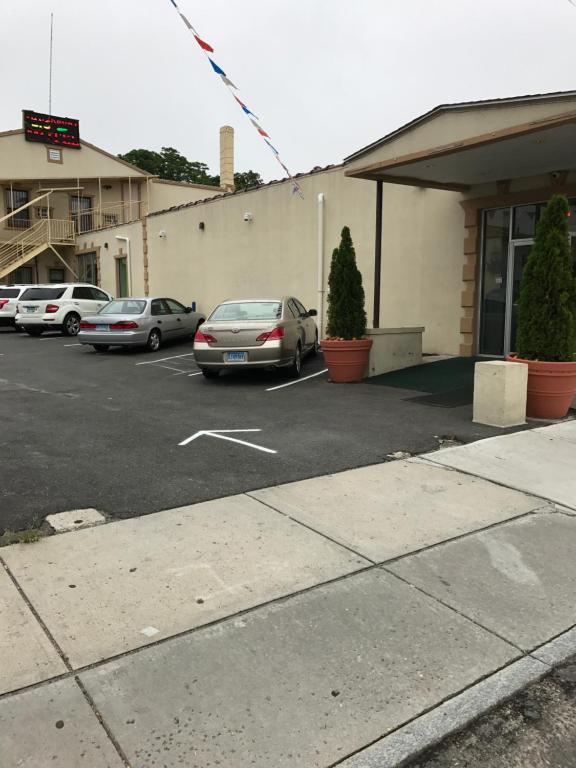 un estacionamiento con autos estacionados frente a un edificio en Waterbury Big Apple Motel, en Waterbury
