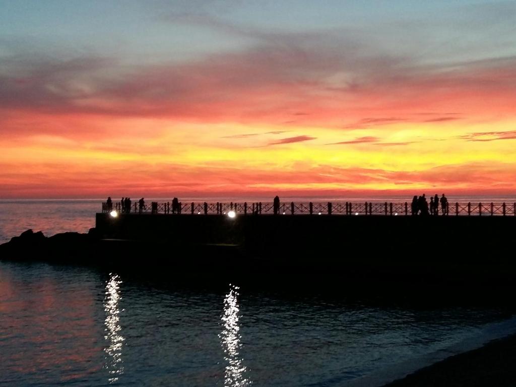a group of people standing on a pier at sunset at Appartamento Larghetto Licastro in Pizzo