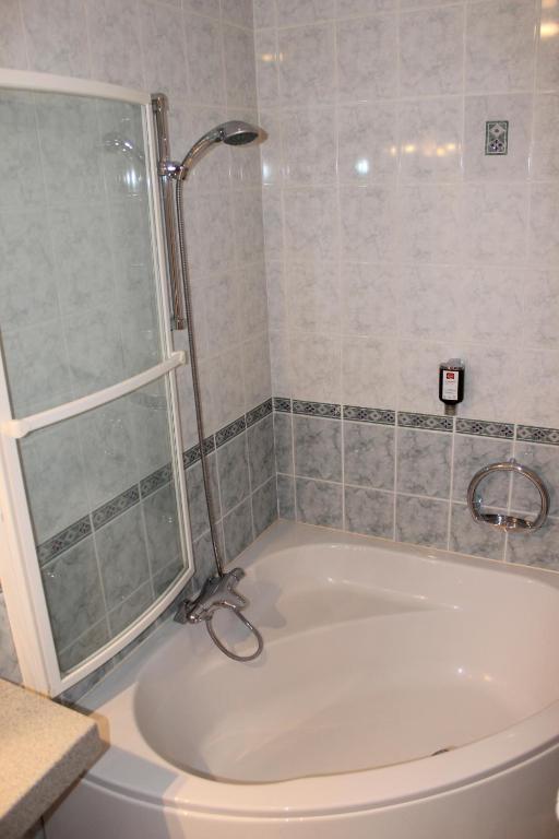 a bathroom with a tub with a shower and a sink at Hotel Bristol in Chalons en Champagne