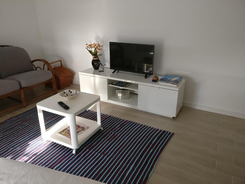 uma sala de estar com uma televisão e uma mesa branca em Casa da Ilha dos Ovos em Aveiro
