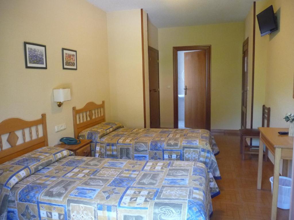 a hotel room with two beds and a table at Hostal Gogar in Puentenansa