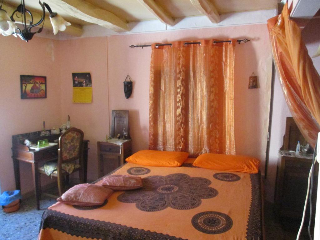 1 dormitorio con cama, escritorio y cortinas en L'Antica Locanda, en Iglesias