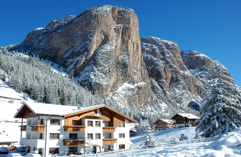 a hotel in front of a mountain in the snow at Garni Hotel Iris in Selva di Val Gardena