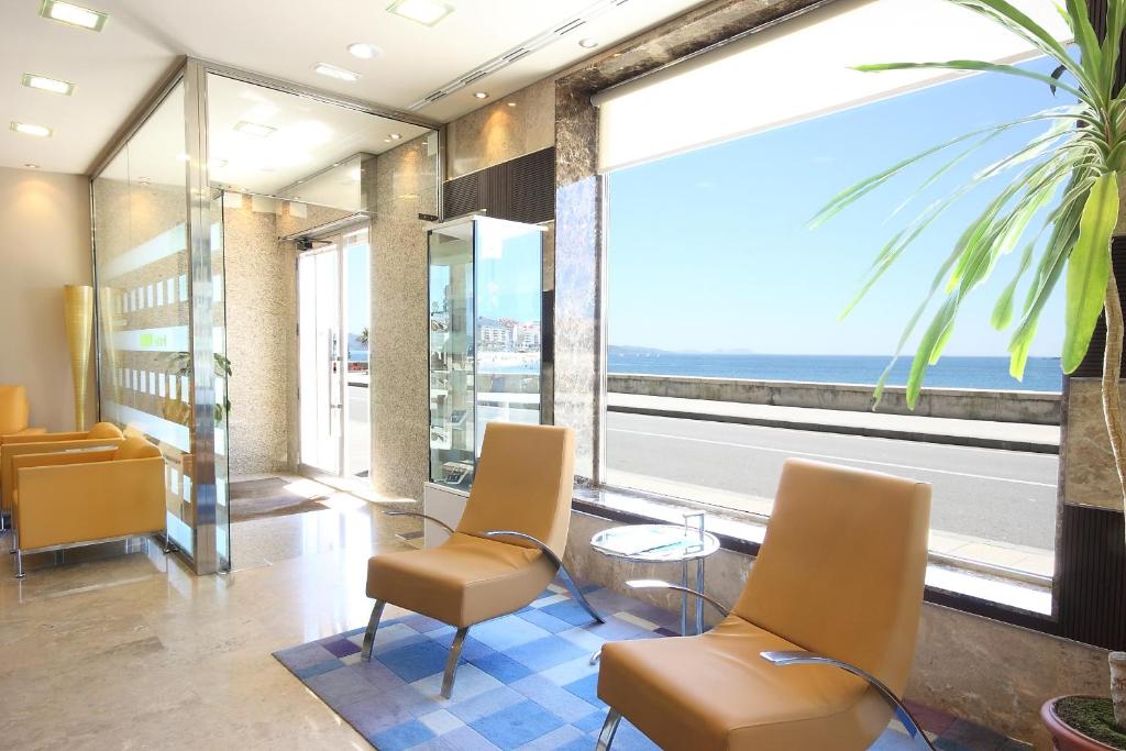 a waiting room with chairs and a view of the ocean at Hotel Minso in Sanxenxo