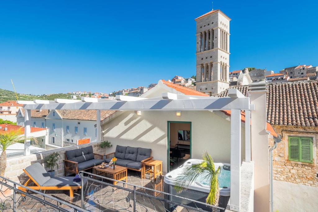 a house with a balcony with chairs and a clock tower at Kalavanda Apartment in Hvar