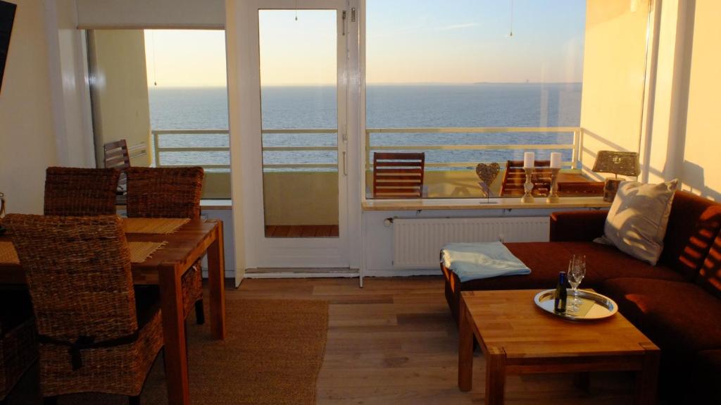 ein Wohnzimmer mit einem Sofa und Tischen sowie einem Balkon in der Unterkunft Mehr Meer geht nicht in Sierksdorf