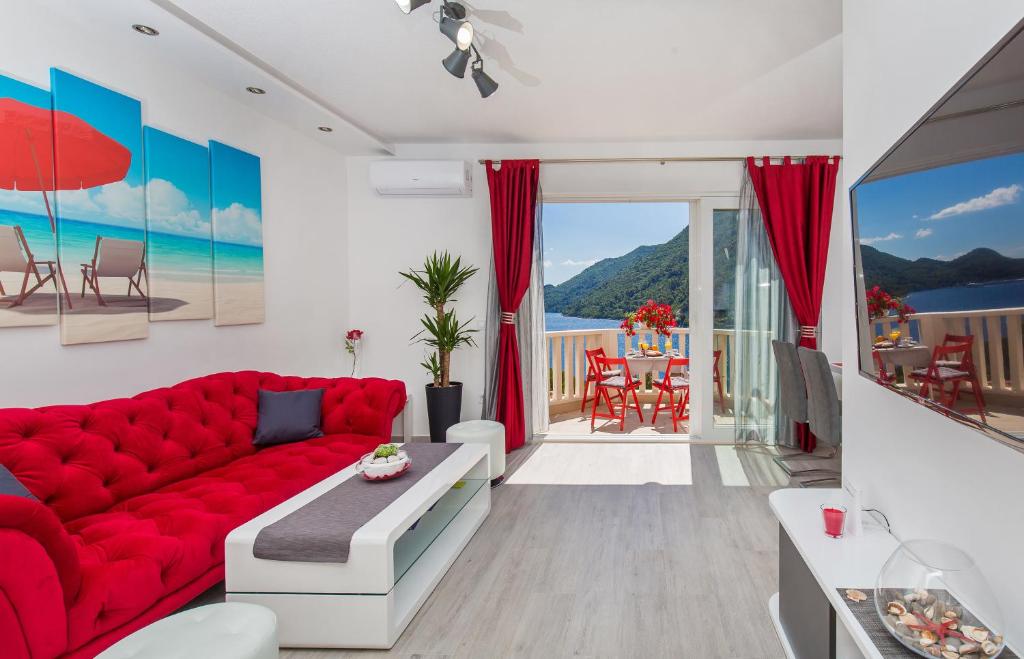 a living room with a red couch and a view of the ocean at Apartments More in Sobra