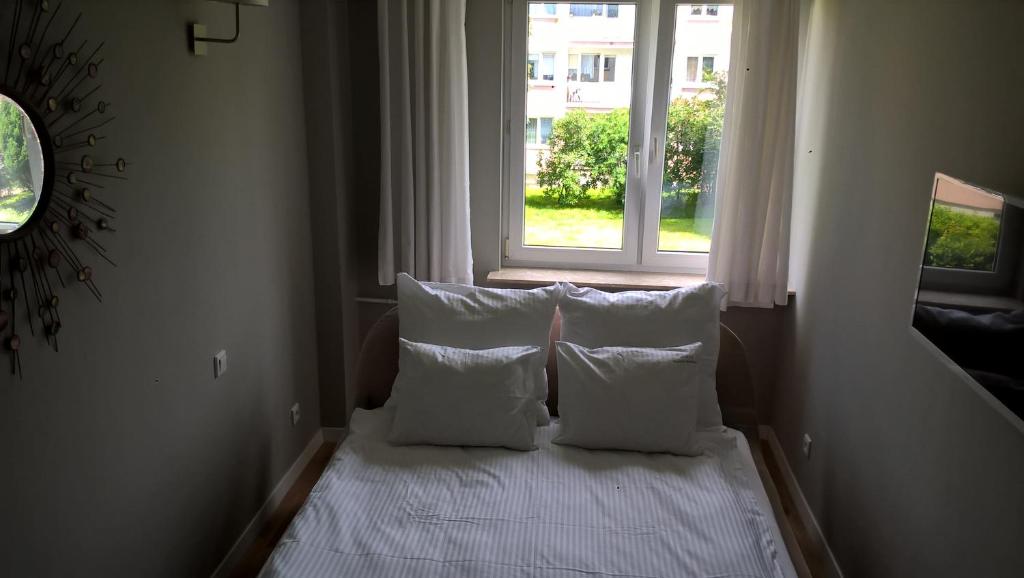 łóżko z białymi poduszkami w pokoju z oknem w obiekcie No.1 Apartments - Kołobrzeg Beach Centrum w Kołobrzegu