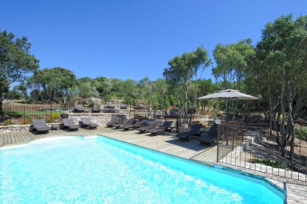 a swimming pool with chairs and an umbrella at Résidence Sophia in Bonifacio