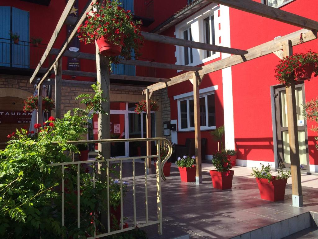 a red building with potted plants in front of it at Hôtel de La Beauronne in Chancelade