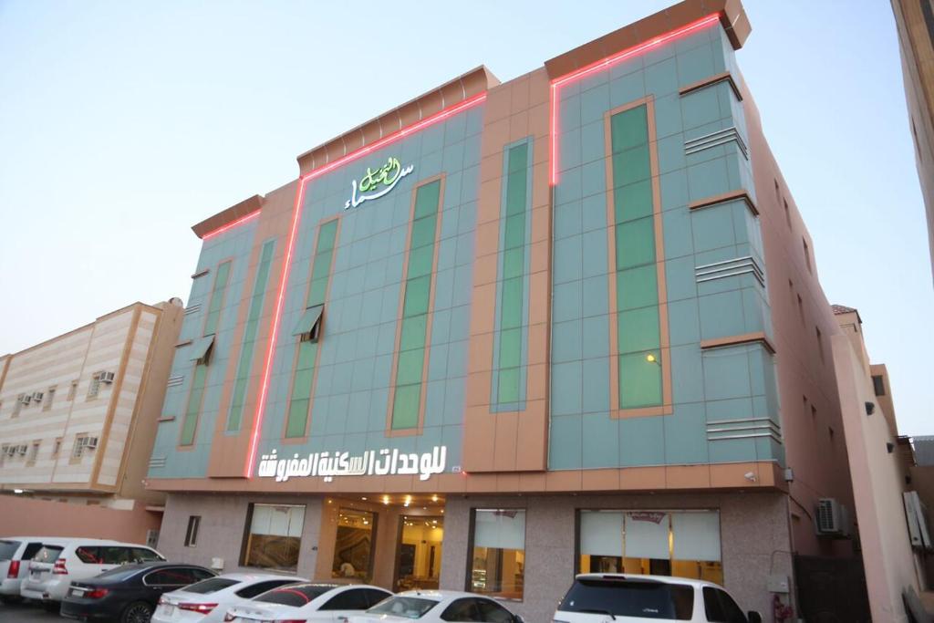 um edifício com carros estacionados num parque de estacionamento em Sama Al Nakheel Furnished Apartments-Families only em Riyadh