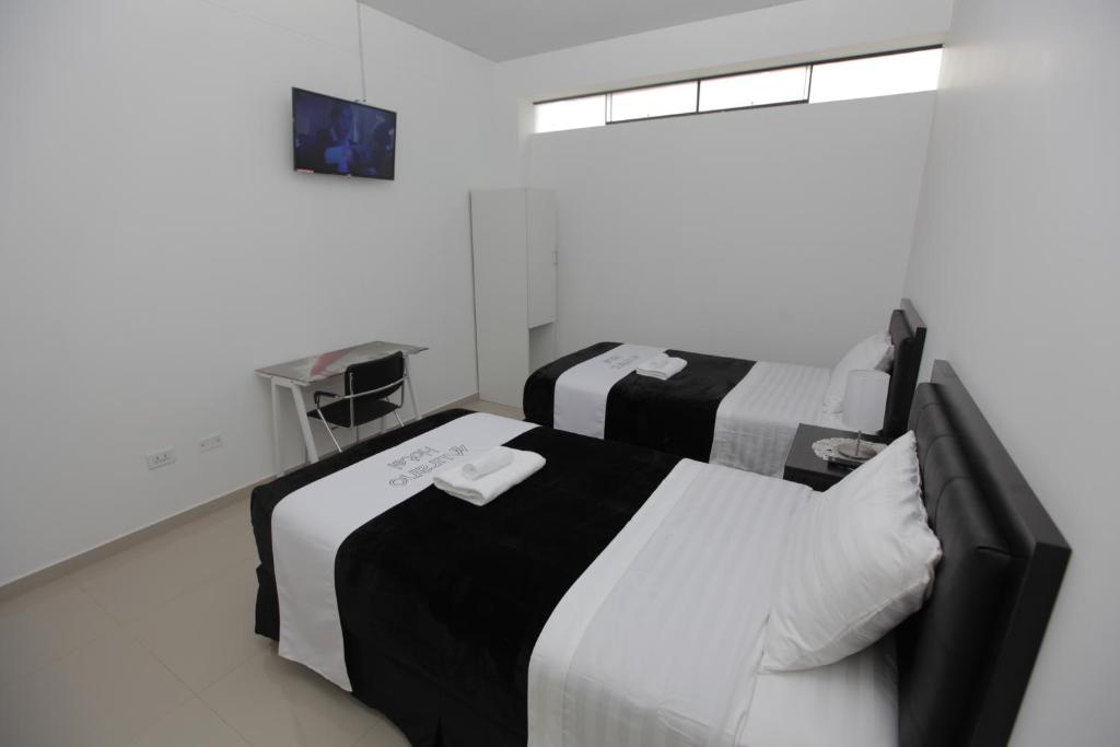 - deux lits dans une chambre blanche et noire dans l'établissement Hotel Murano, à Abancay