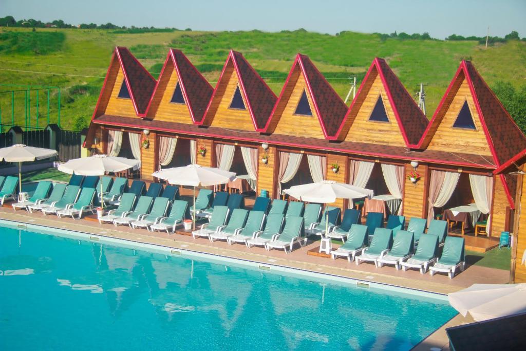 a swimming pool with chairs and umbrellas in front of a hotel at Usadba Berezino in Zarvantsy